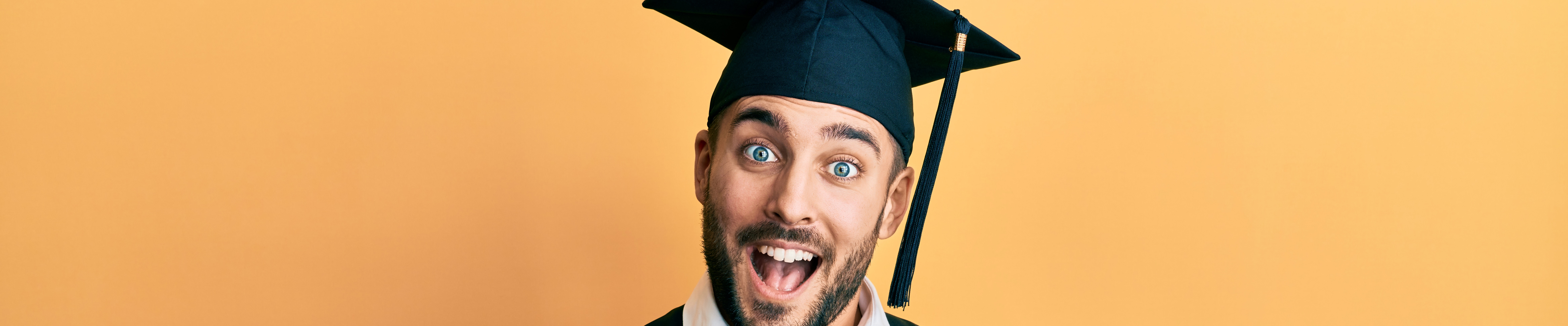 alt="gezicht lachende man met afstudeerhoed op"