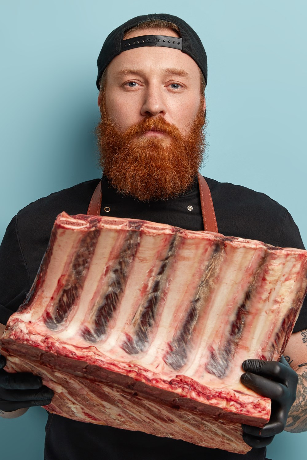 alt="slager presenteert ribstuk in beide handen"