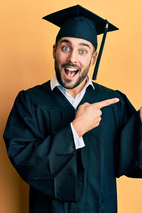 alt="jonge man met toga en afstudeerhoed maakt dansend gebaar"