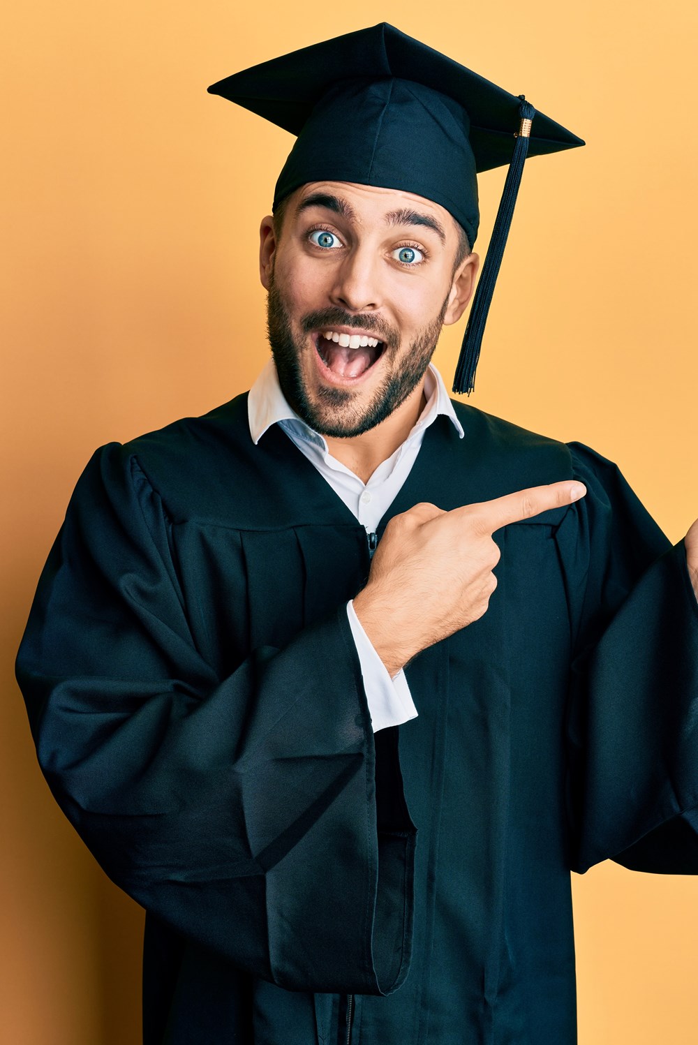 alt="jonge man met toga en afstudeerhoed maakt dansend gebaar"