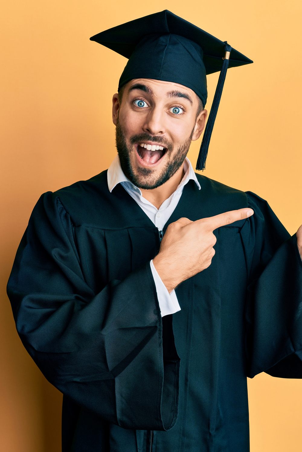 alt="jonge man met toga en afstudeerhoed maakt dansend gebaar"