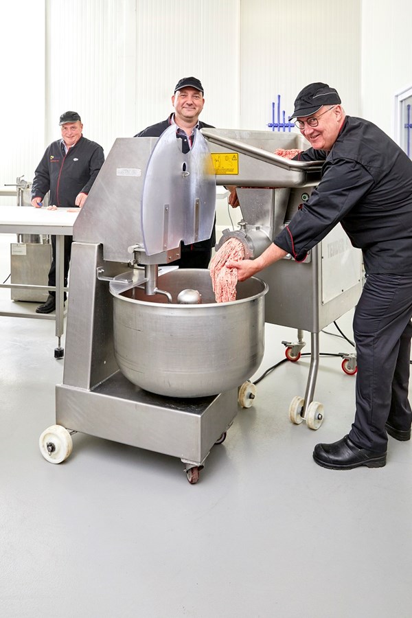 Drie leerkrachten slagerij maken gehakt en lachen 
