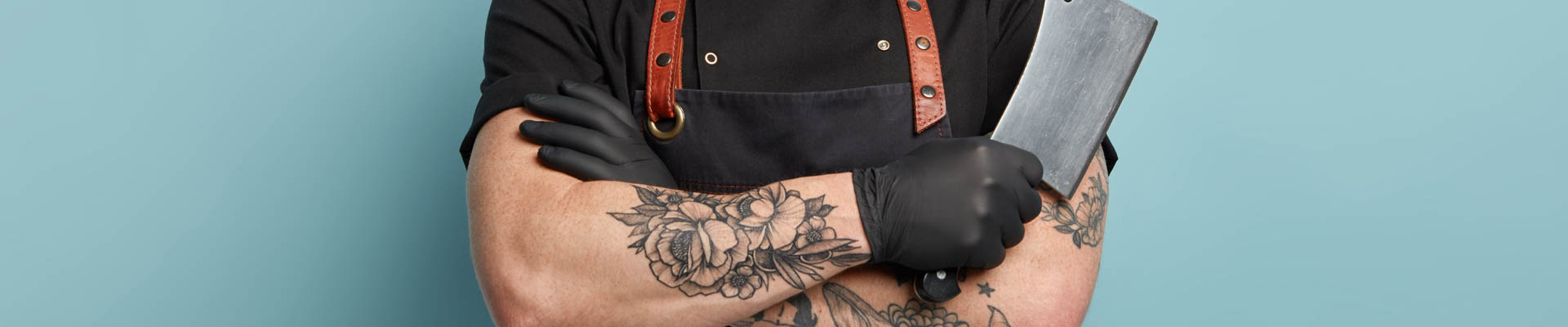 alt="detail romp slager met gekruiste armen en hakmes in rechter hand"