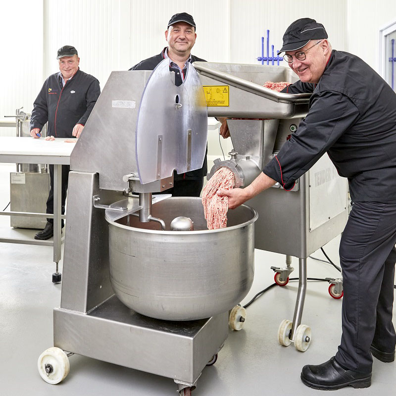 Drie leerkrachten slagerij maken gehakt en lachen 