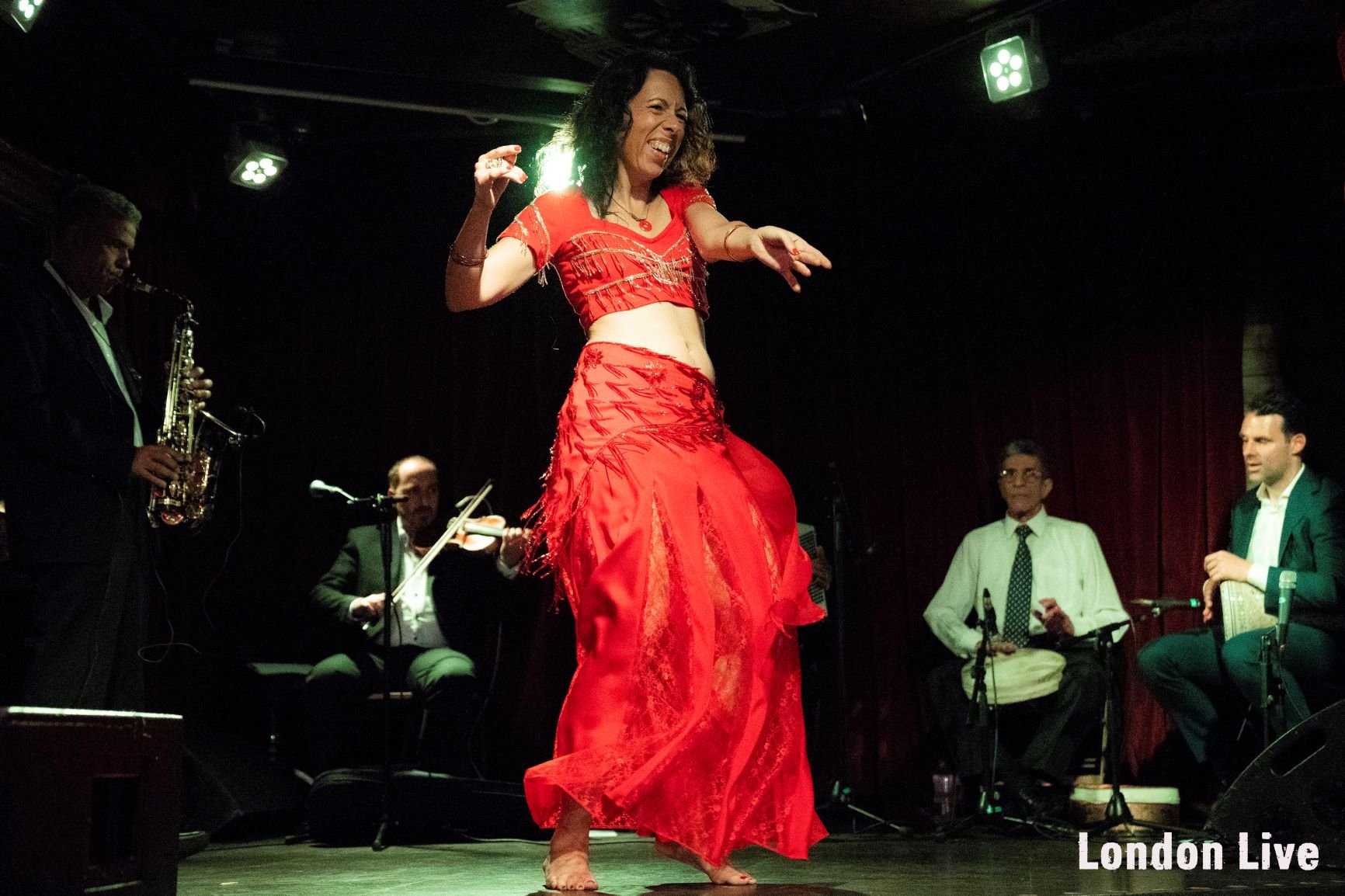 Buikdanseres op  het podium met rode rok en kort rood topje