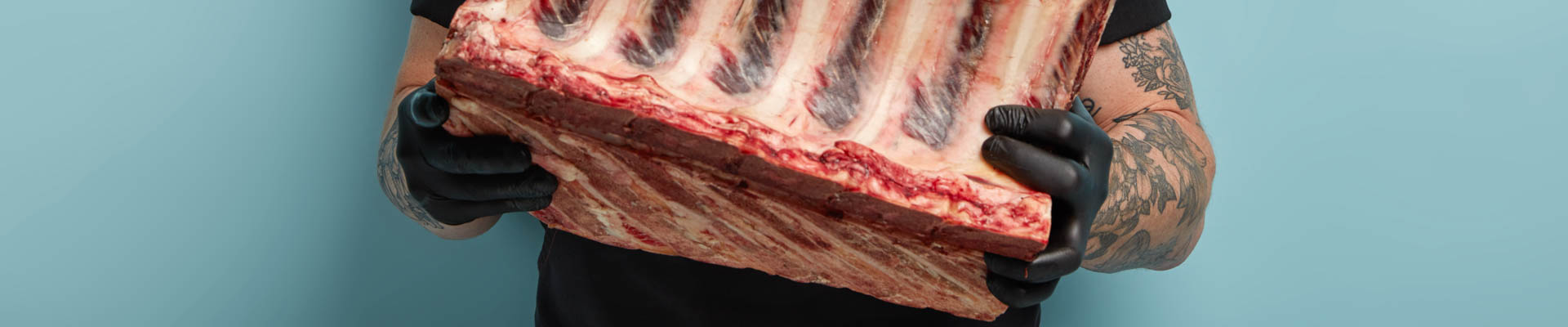 alt="romp slager met groot ribstuk in beide handen"