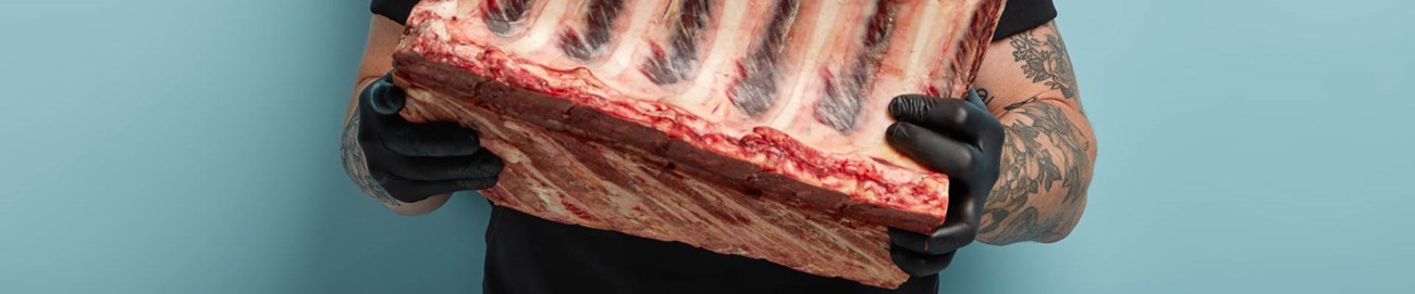 alt="romp slager met groot ribstuk in beide handen"